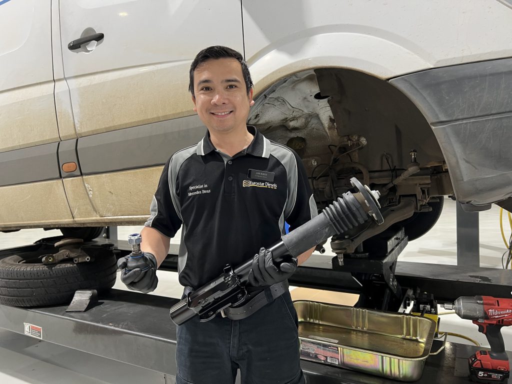 Expert technician holding suspension and steering components before installation on a mercedes