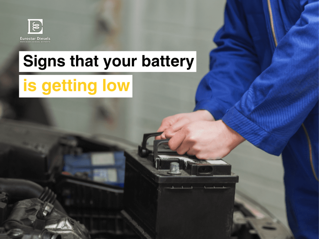 A person in a blue uniform is handling a car battery under an open vehicle hood. The text "Signs that your battery is getting low" is displayed, with "low battery" highlighted in yellow. The Eurostar Diesels logo is visible in the top left corner.
